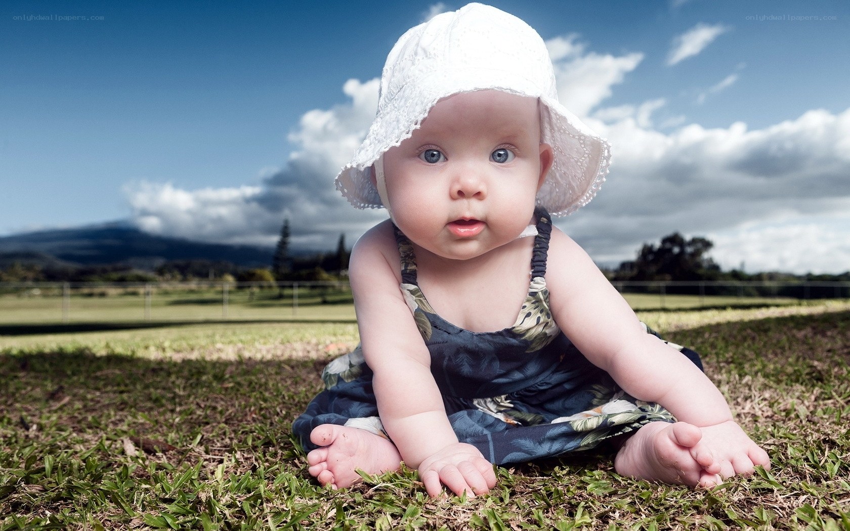 Baby in white hat on grass