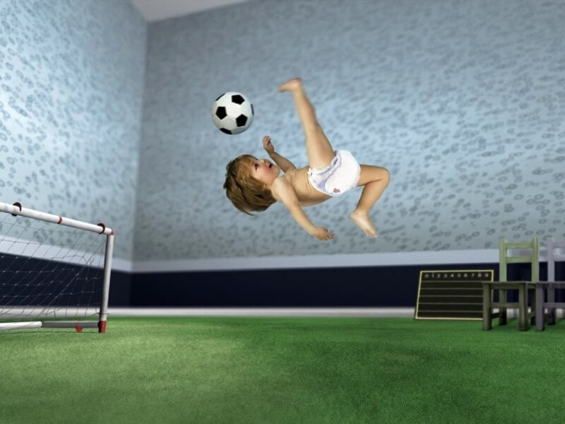 Baby playing soccer in a room