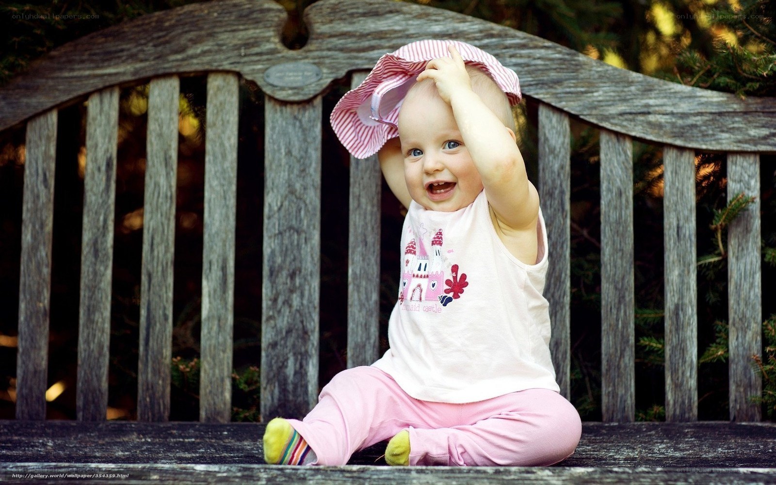 Baby playing with hat on bench