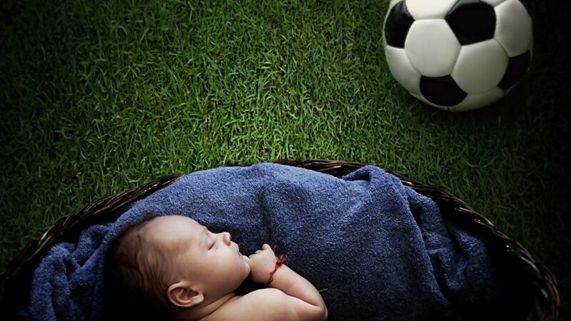 Baby sleeping on grass with soccer ball