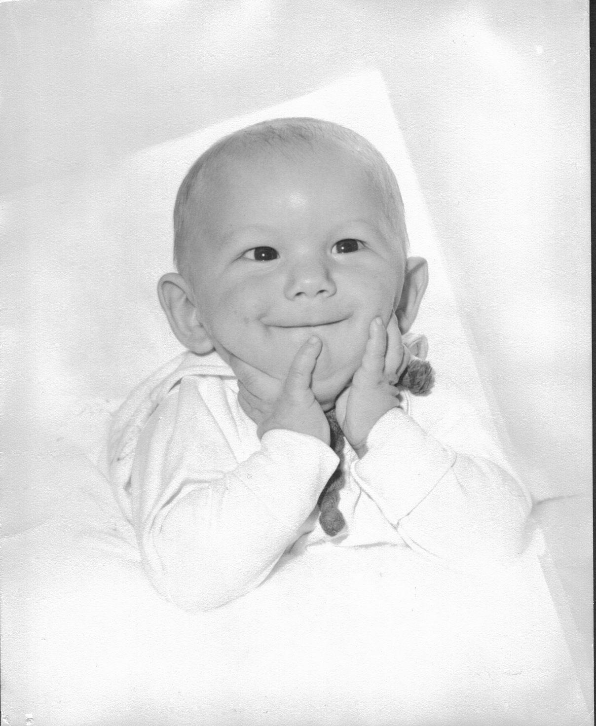 Baby smiling with hands on cheeks