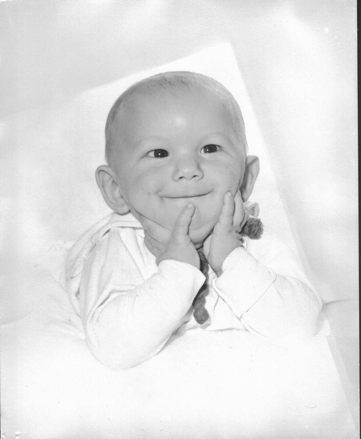 Baby smiling with hands on cheeks