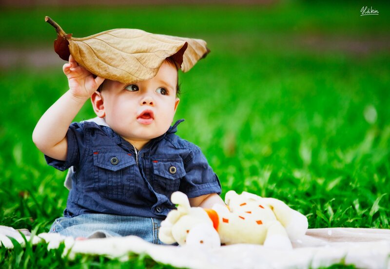 Baby with leaf hat on grass