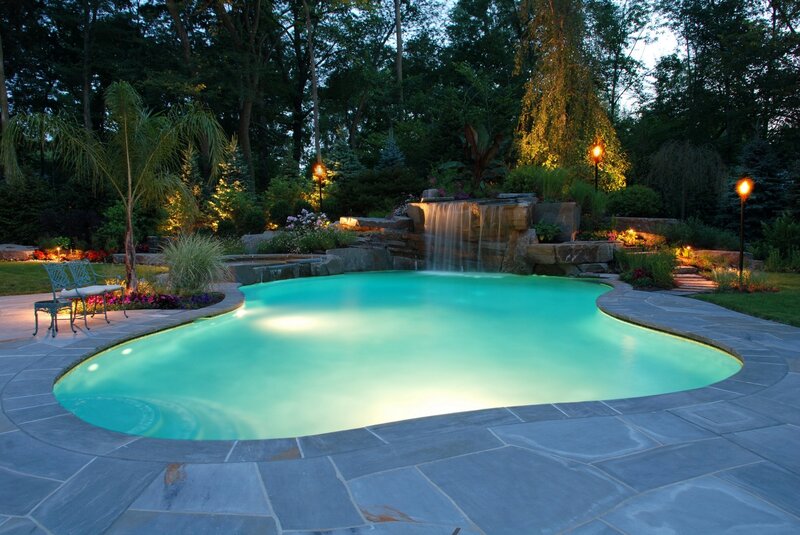 Backyard pool with waterfall at dusk