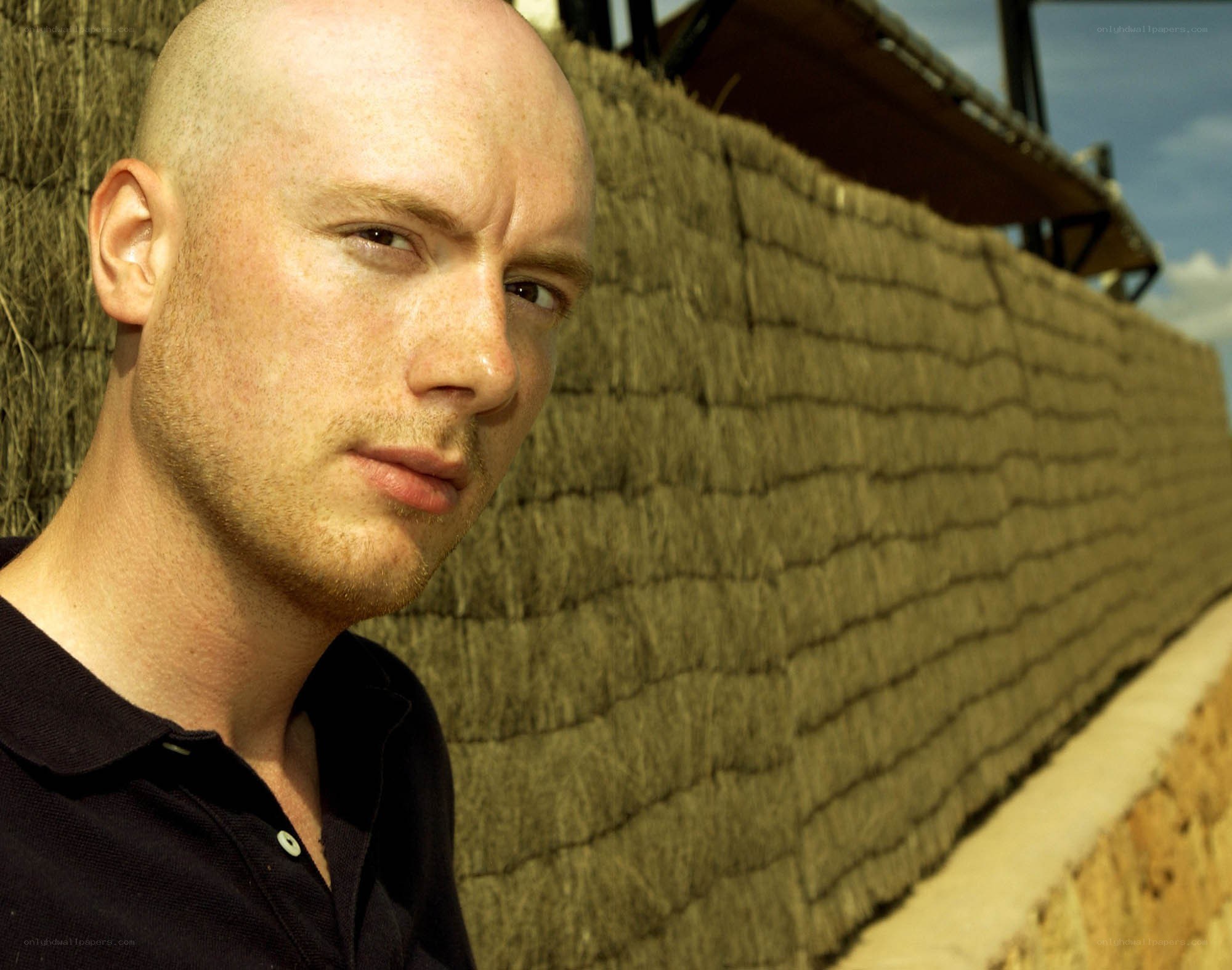 bald man against straw wall