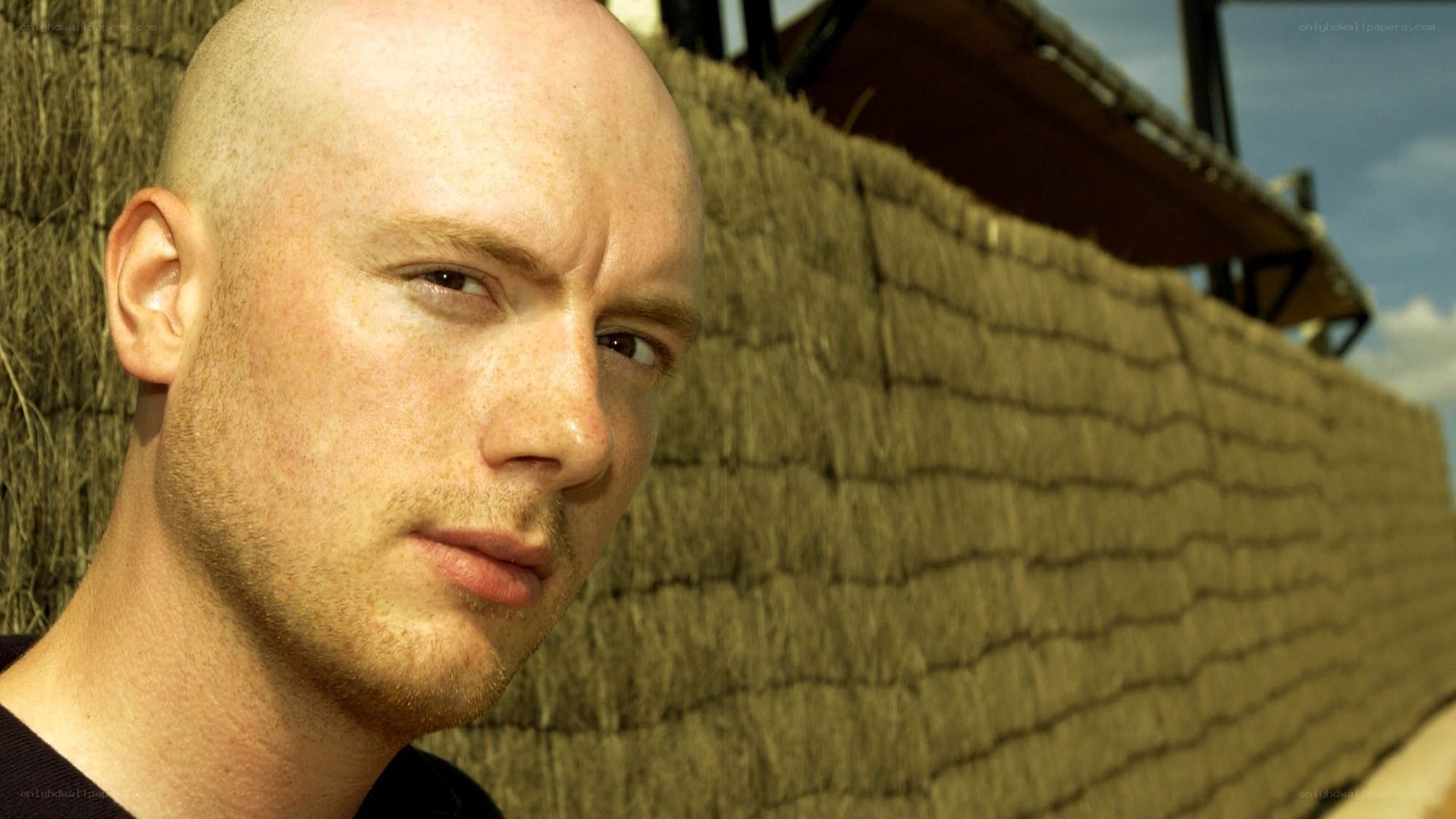 bald man against straw wall