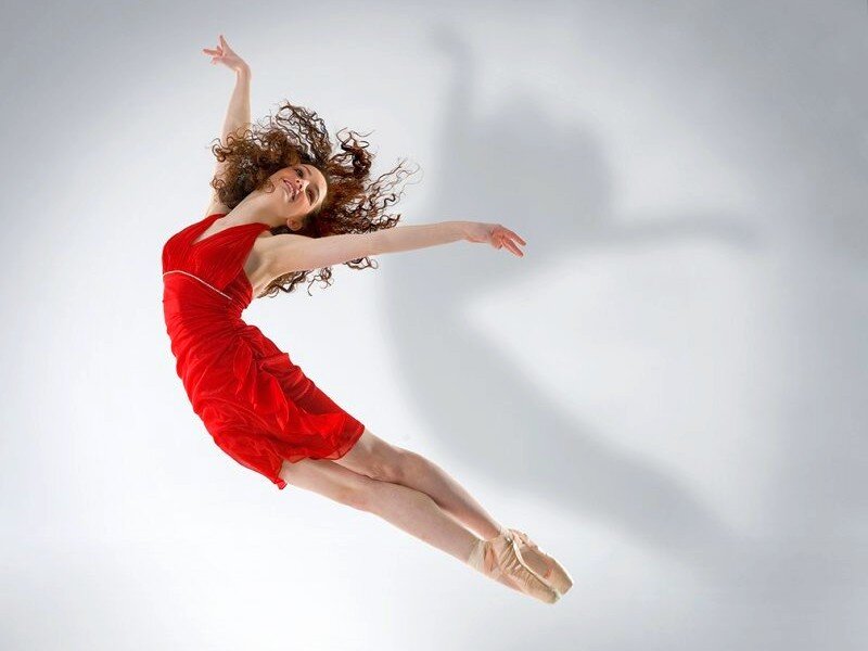 Ballerina in red dress mid-jump