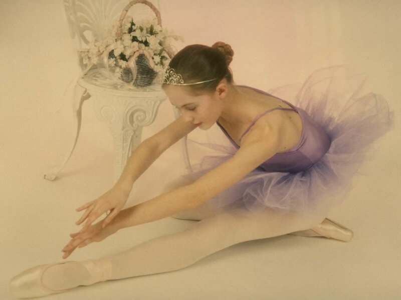 Ballerina stretching in purple tutu
