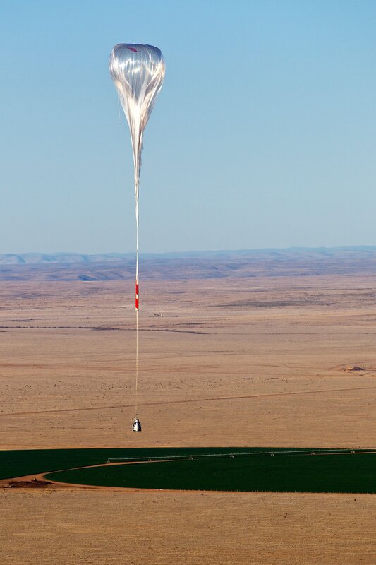 Balloon carrying payload over desert