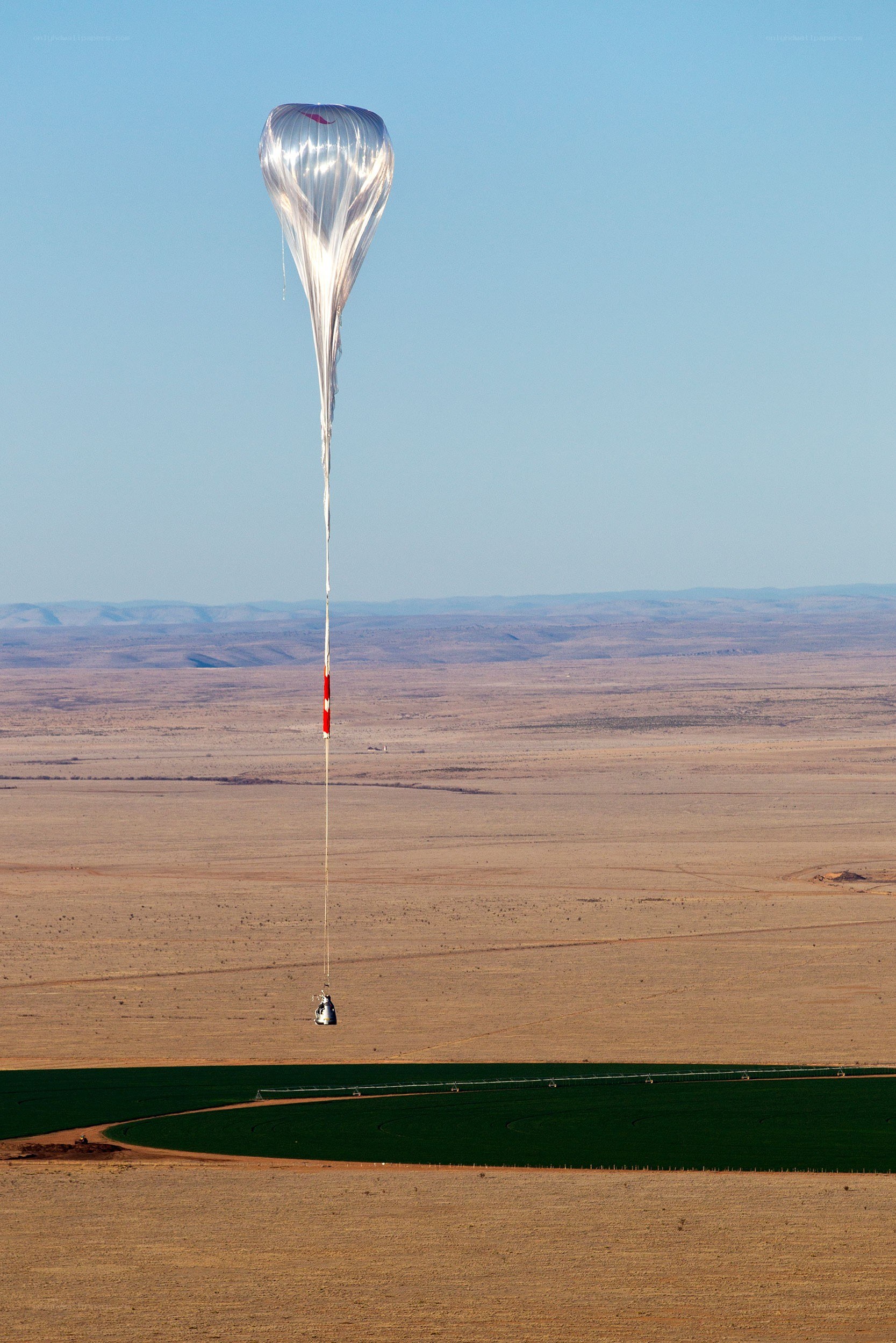 Balloon carrying payload over desert