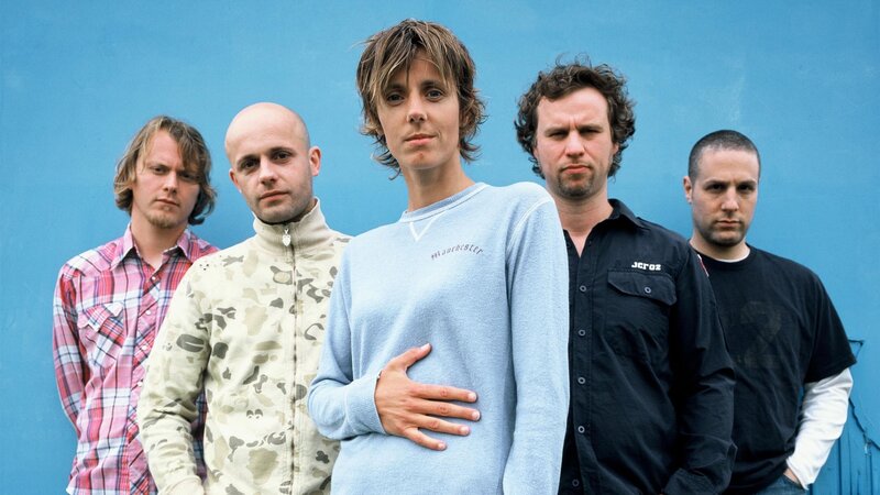 band members in front of blue wall