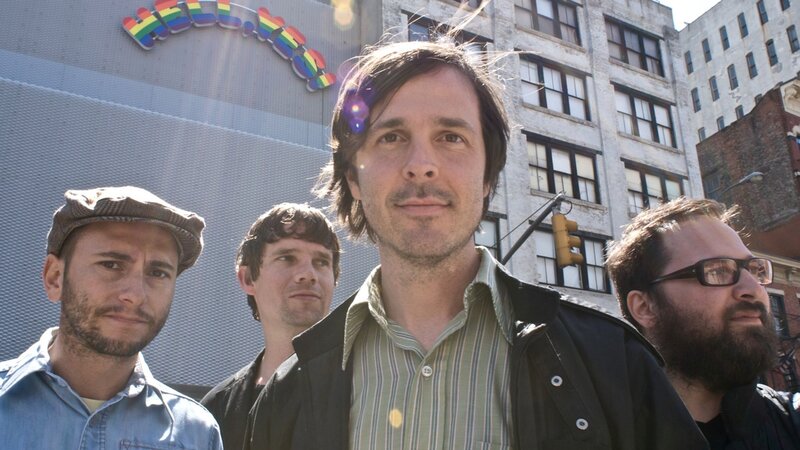 band members in front of rainbow sign