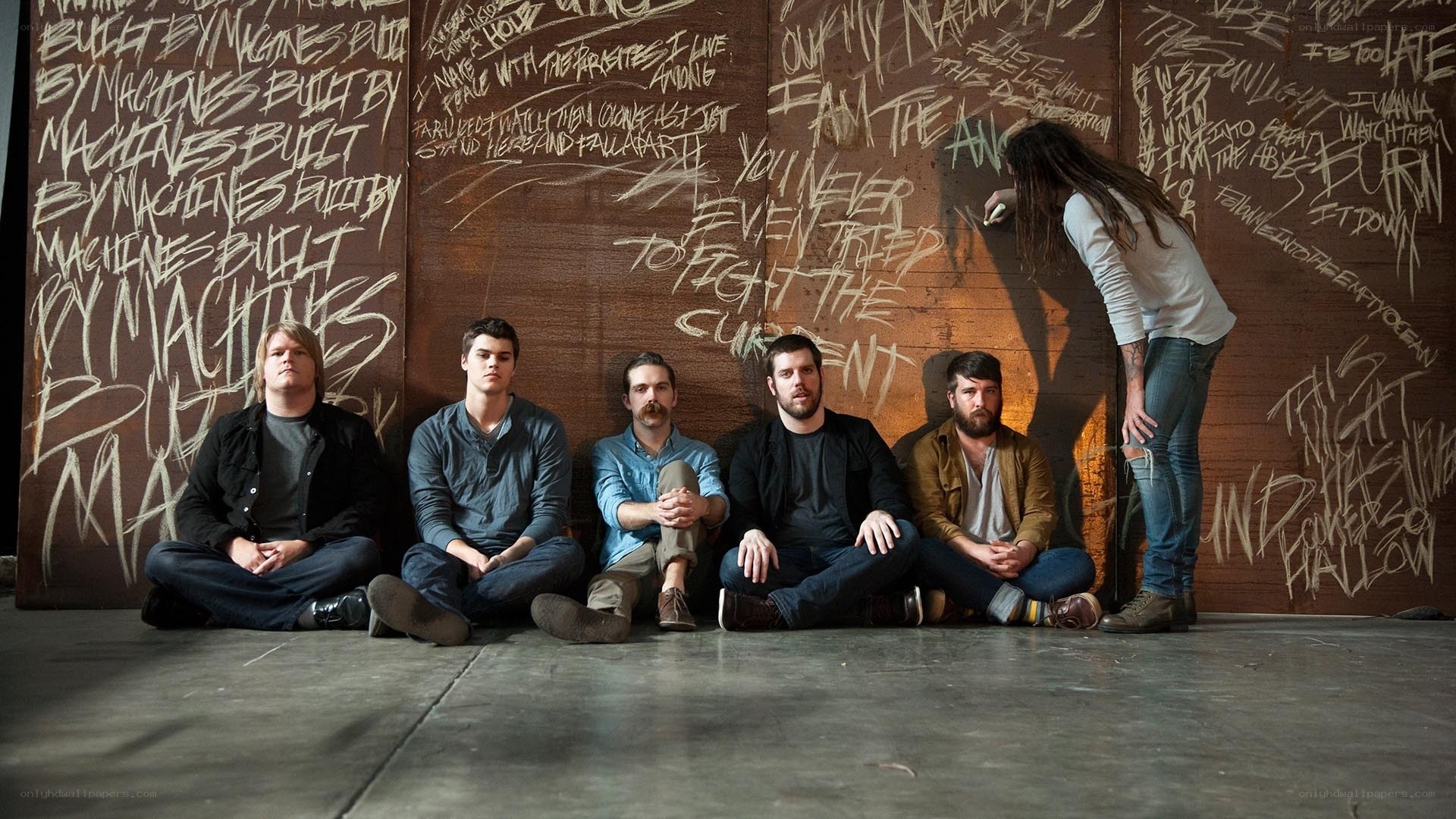 band members on floor with graffiti wall