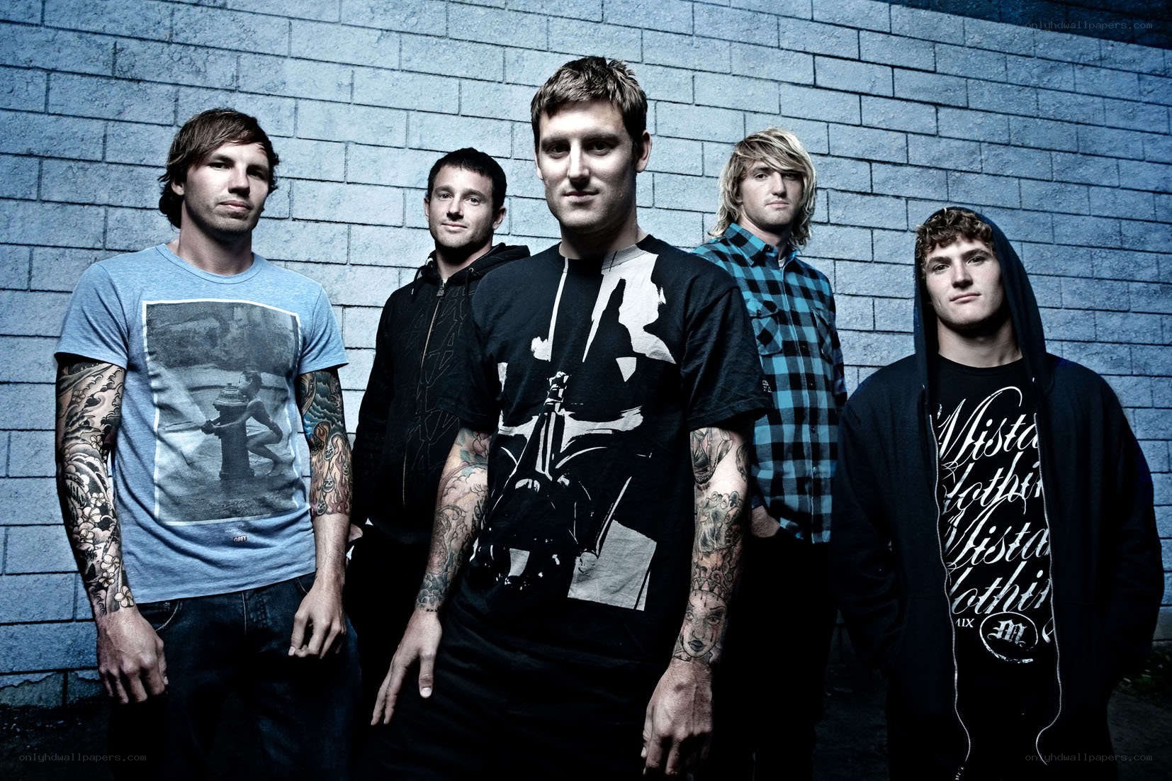 band members posing against brick wall