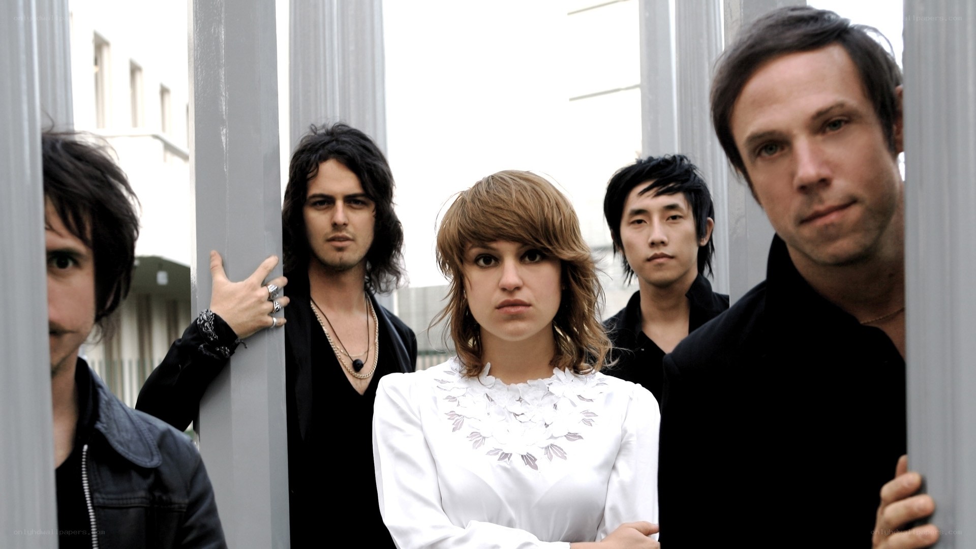 band members posing behind pillars