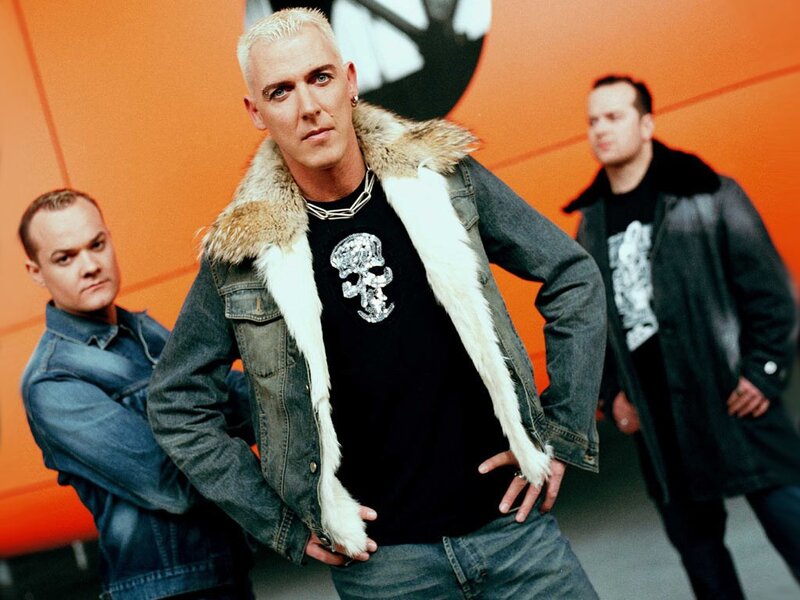 band members posing in front of orange wall