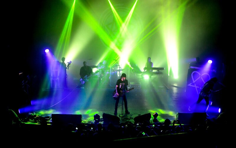 Band Performing on Stage — Green, Energetic, Night, Photograph, Guitarist