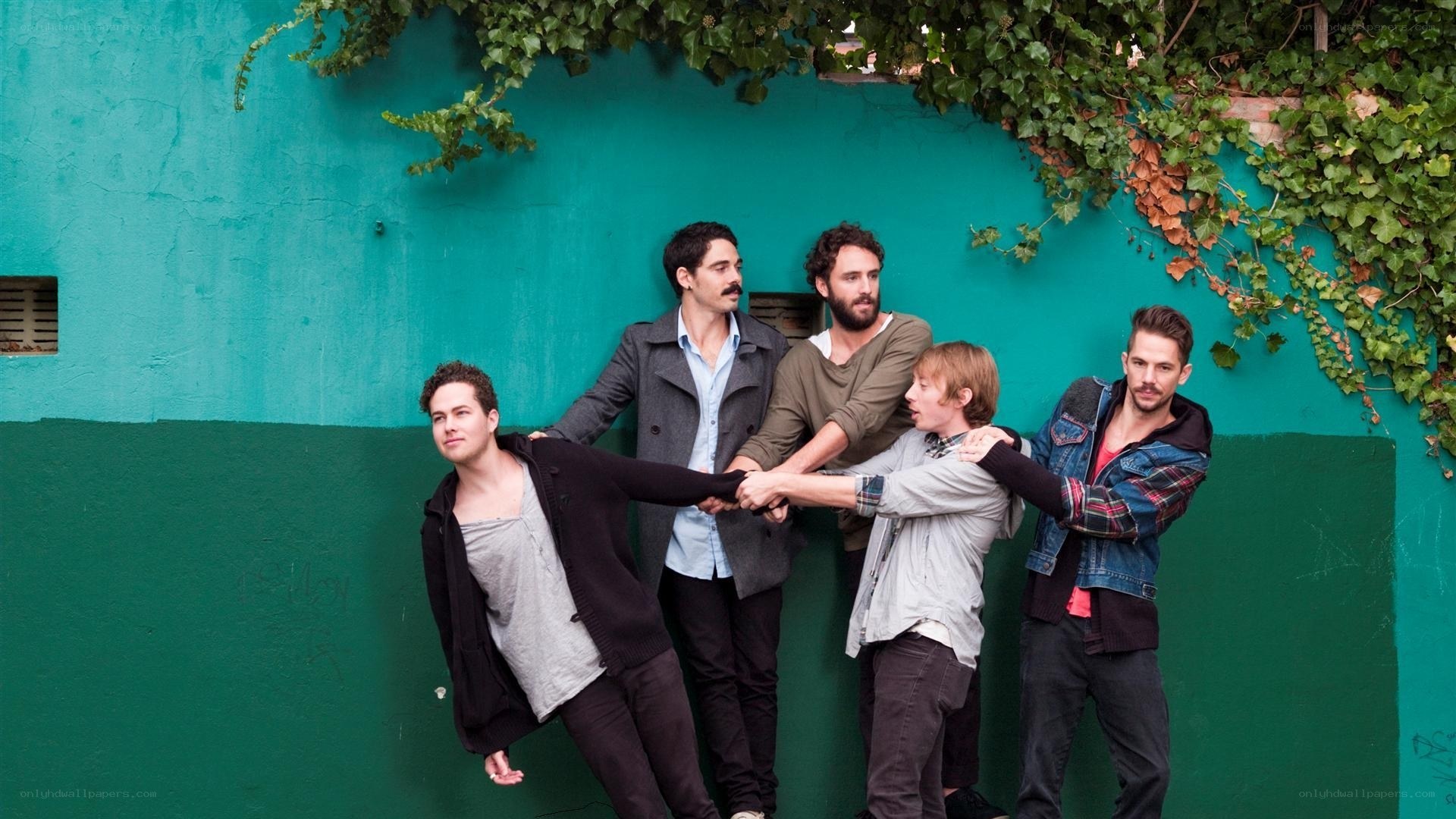 band posing against green wall