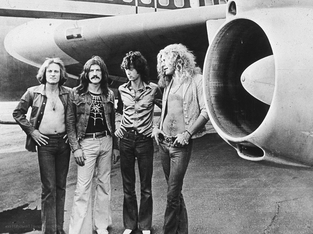 Band posing by airplane