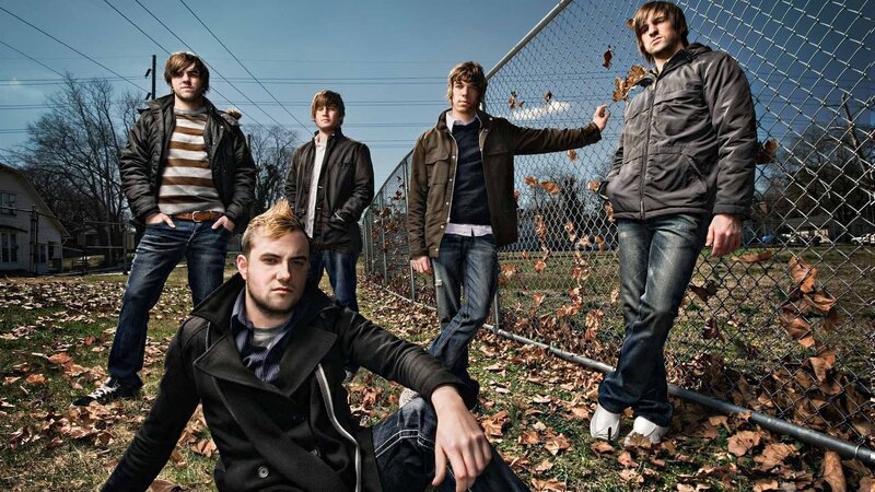 band posing by fence