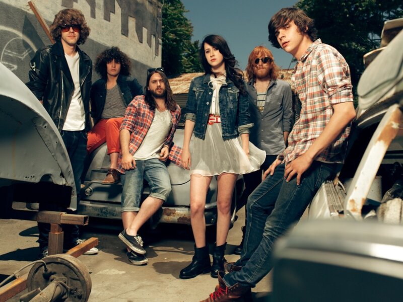 band posing with vintage cars