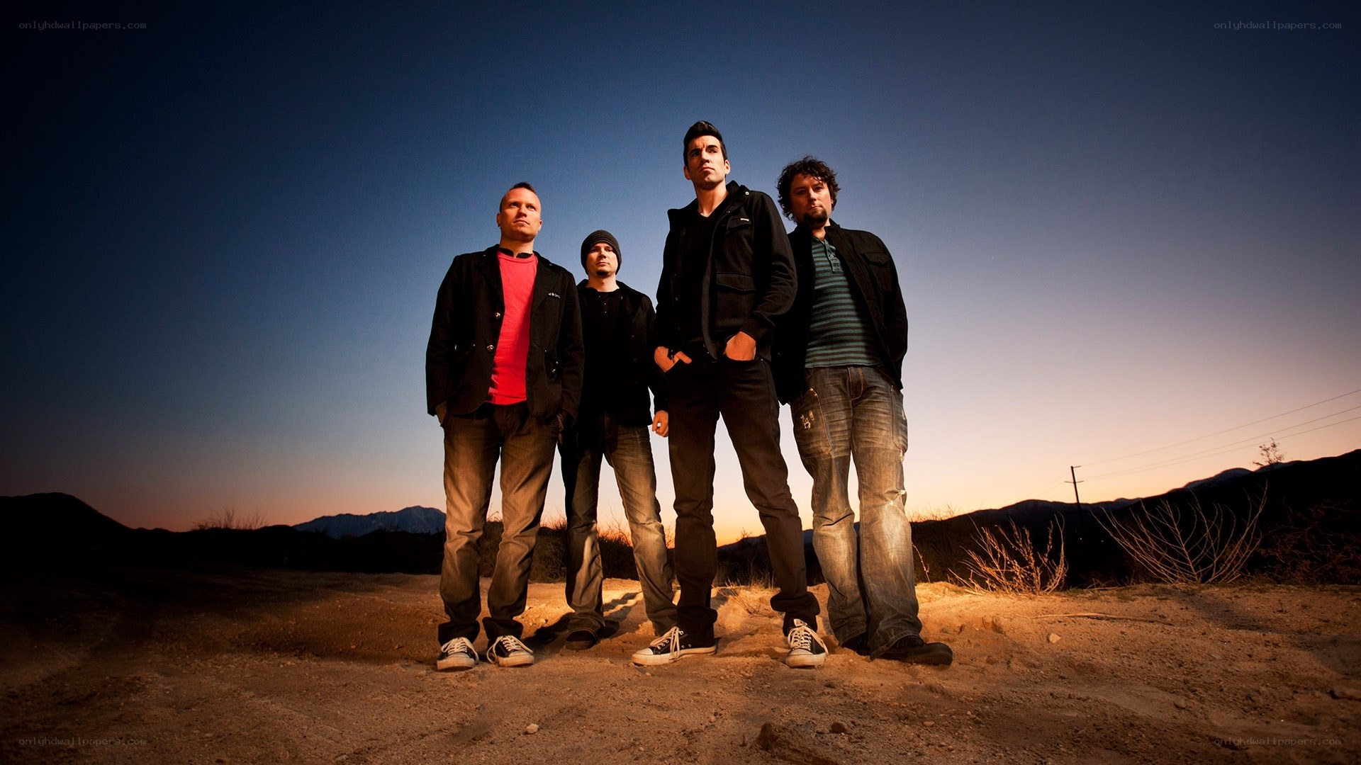 band standing in desert at dusk