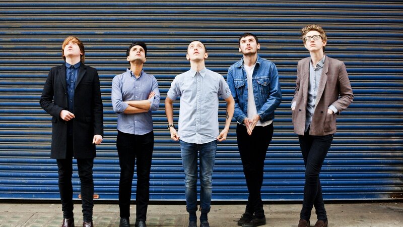 band standing in front of blue shutter