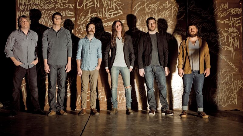 band standing in front of graffiti wall