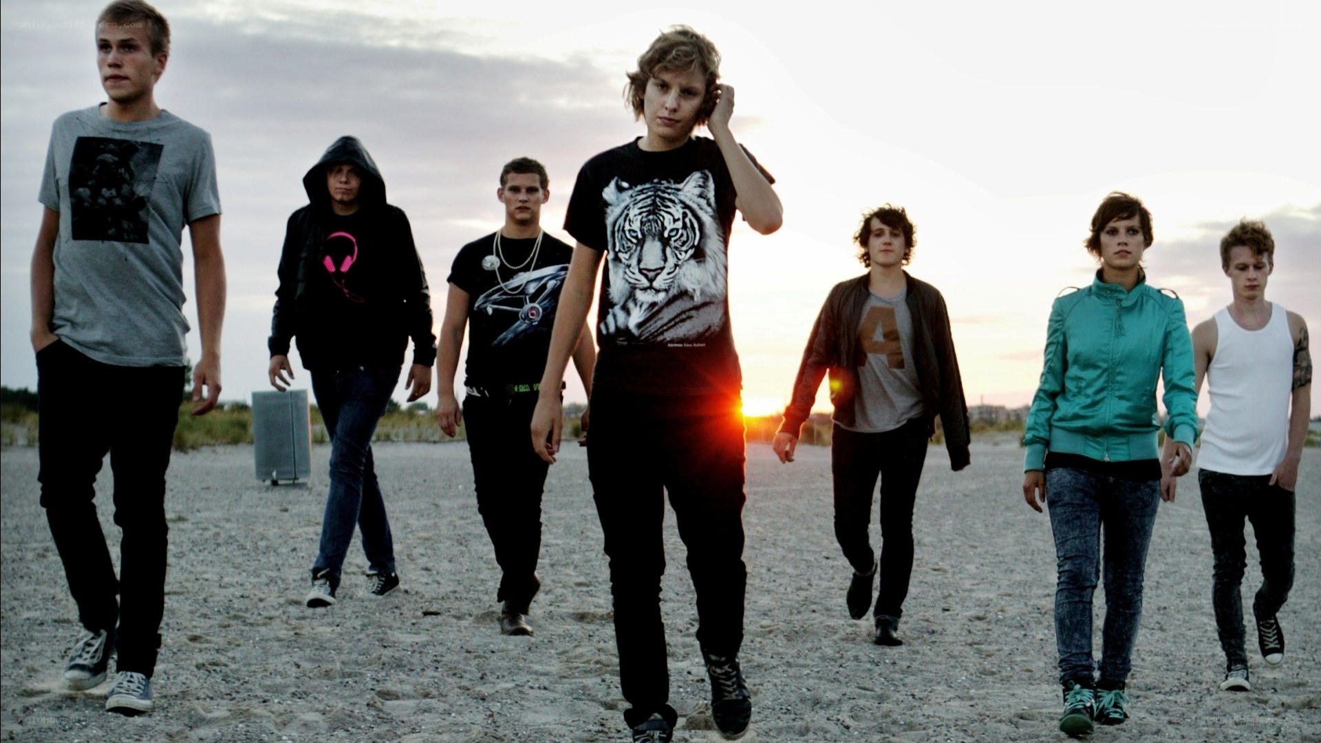 band walking on beach at sunset