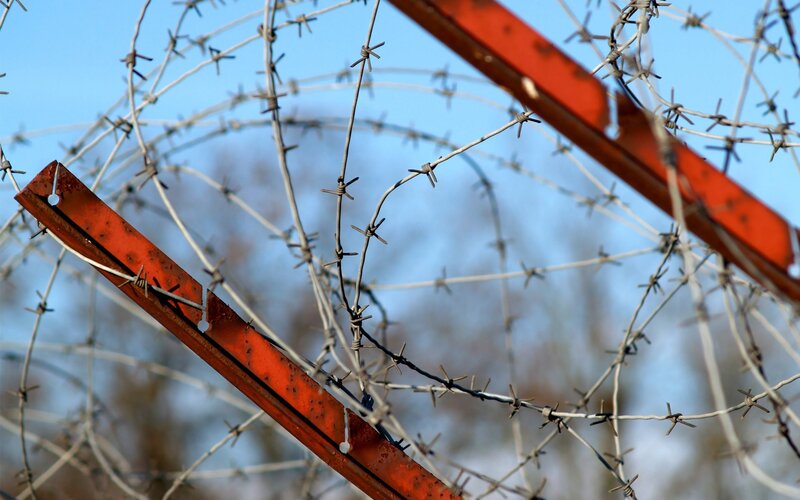Barbed wire fence against blue sky