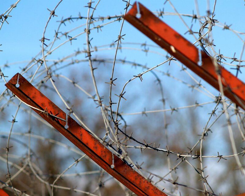 barbed wire fence against blue sky