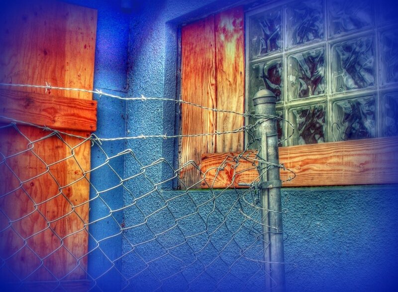 barbed wire fence by boarded window