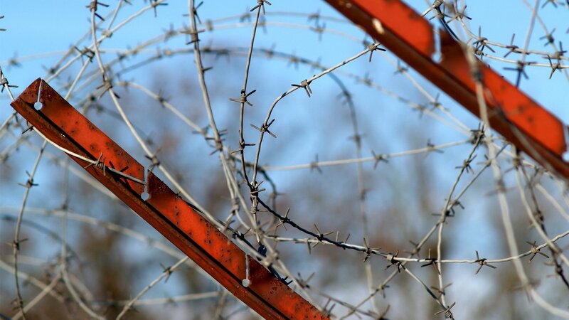 Barbed wire fence with red metal