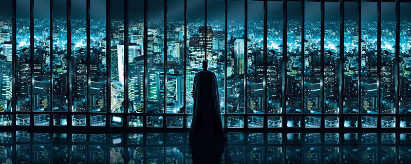 Batman overlooks a city at night