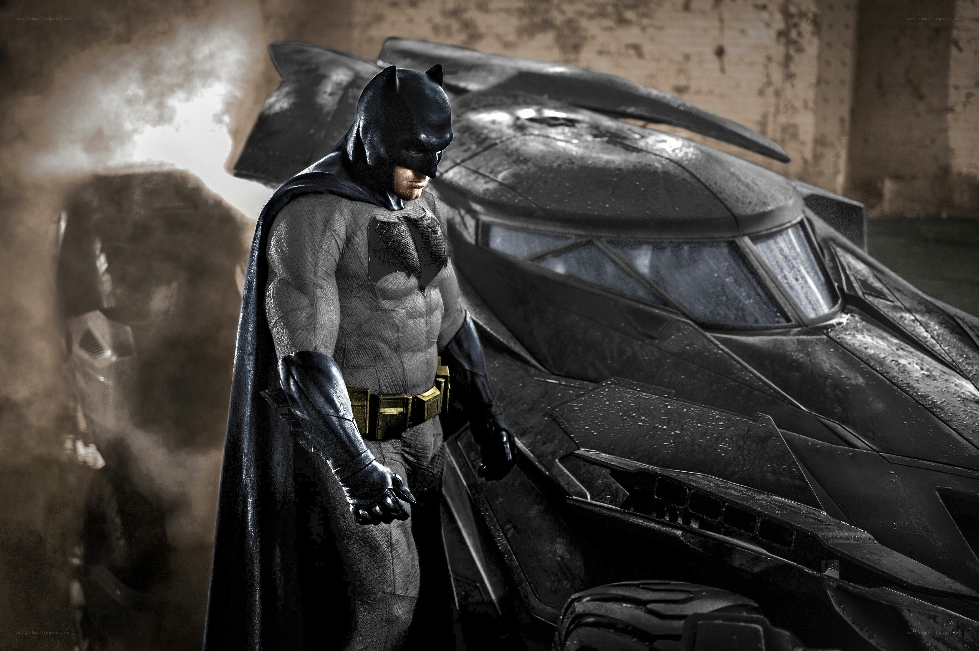 Batman stands beside Batmobile
