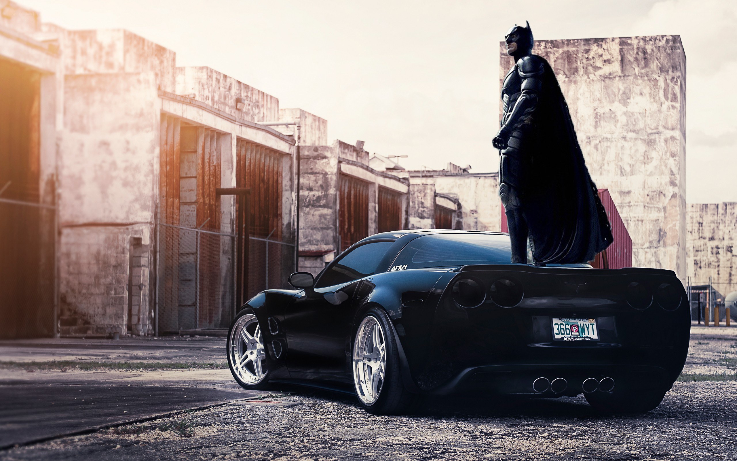Batman stands on a black car