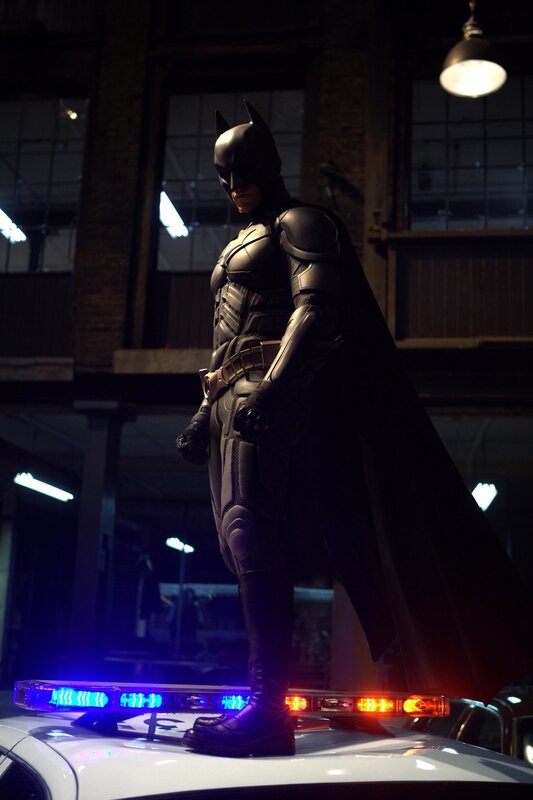 Batman stands on a police car