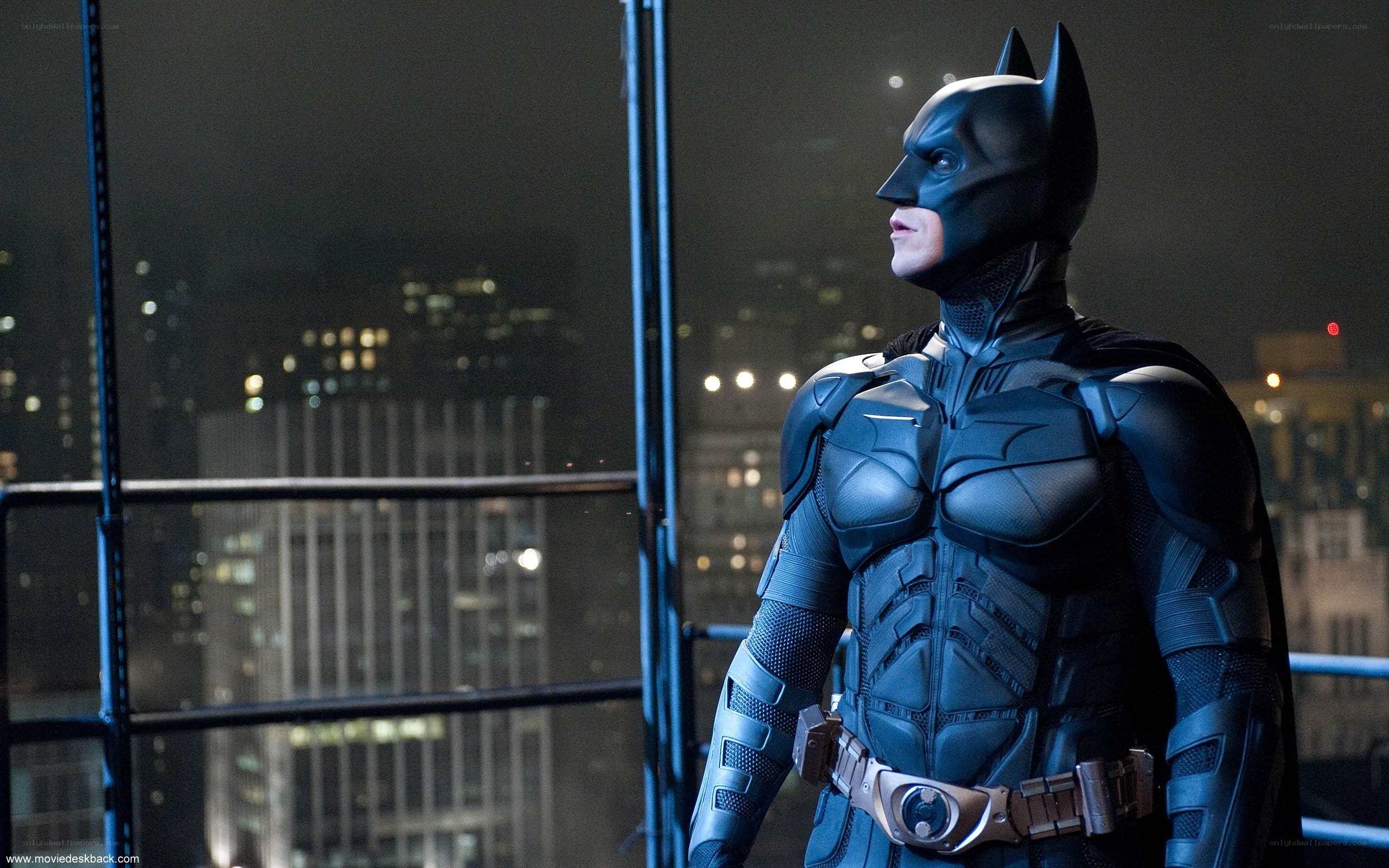 Batman stands on a rooftop at night
