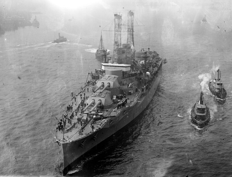 Battleship being towed by tugboats