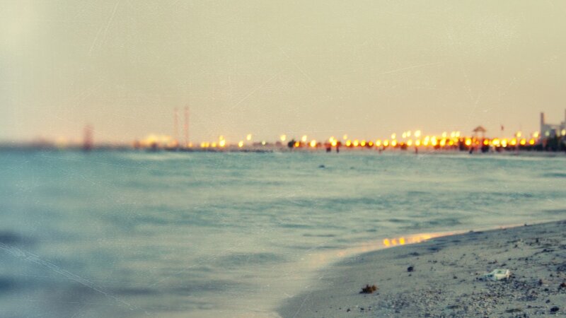 beach at dusk with city lights