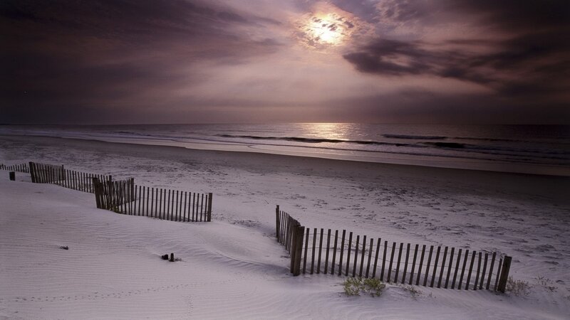 Beach at dusk with wooden fence