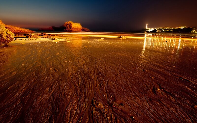 Beach at night with city lights
