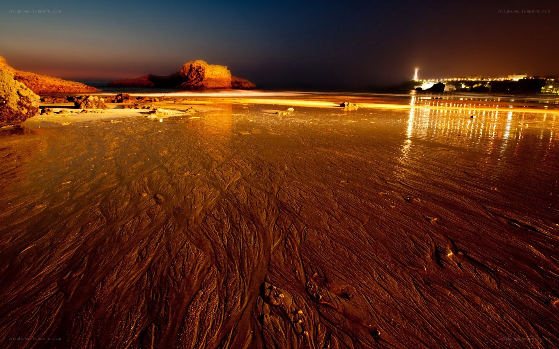 Beach at night with city lights