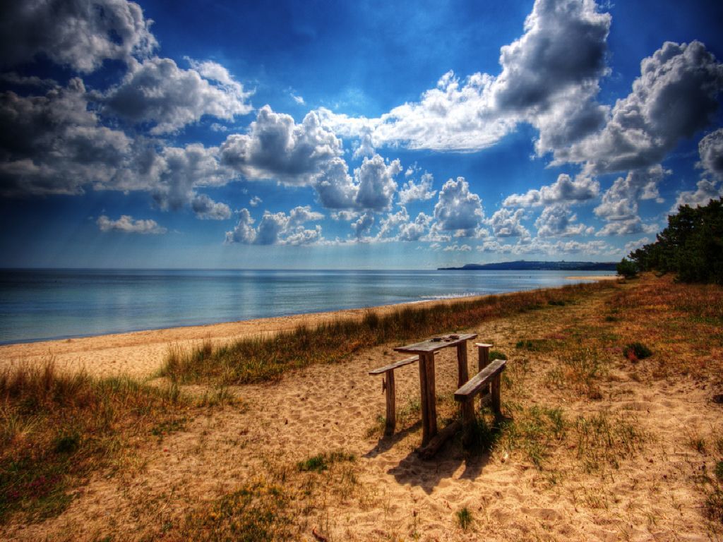 Beach bench under cloudy sky