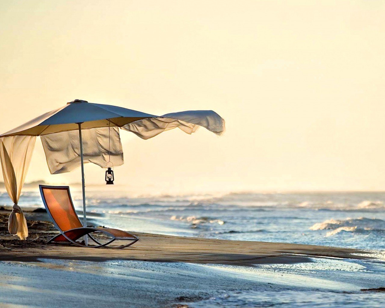 Beach chair under umbrella at sunset