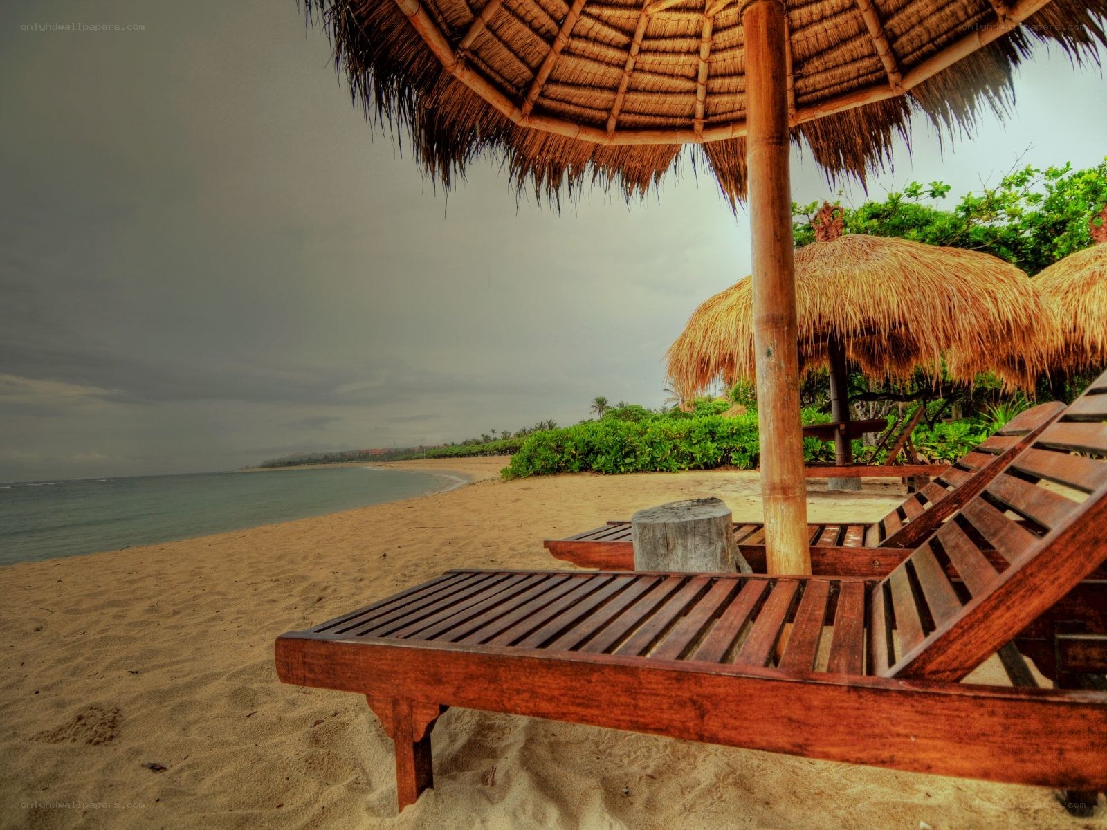 Beach lounge chairs under thatched umbrellas