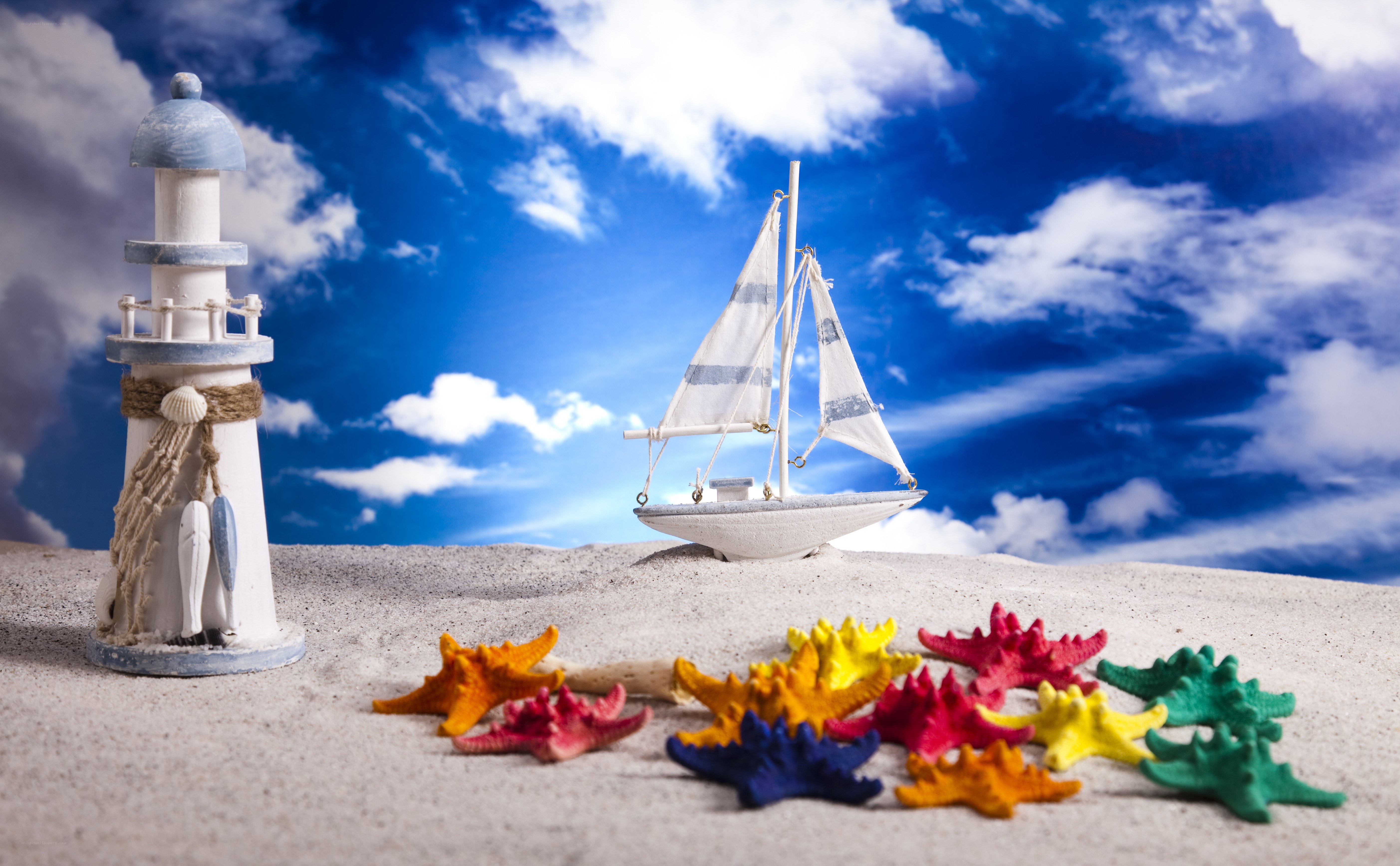 Beach scene with lighthouse and sailboat