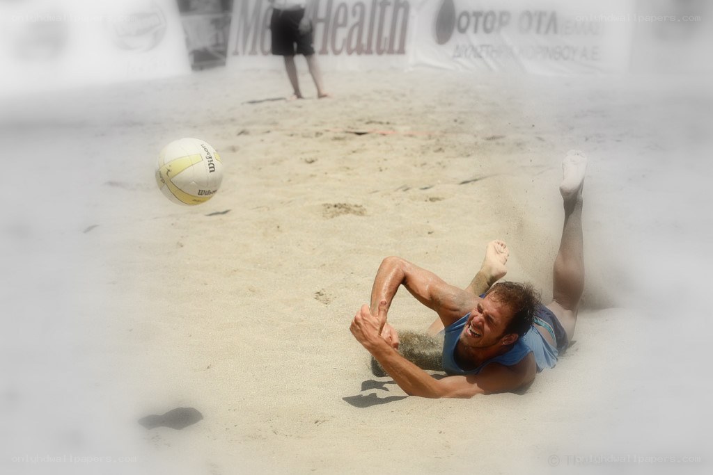 Beach volleyball player diving for ball