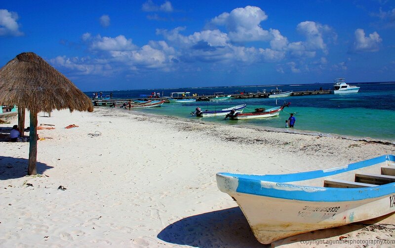 Beach with boats and thatched umbrella