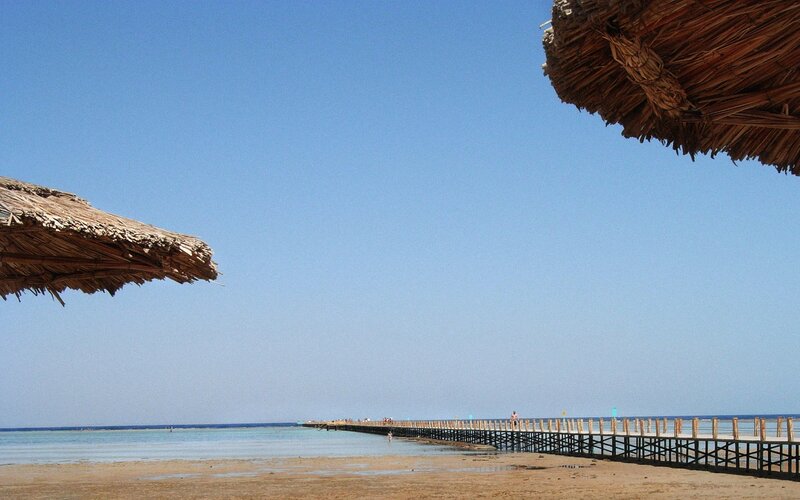 Beach with pier and thatched umbrellas